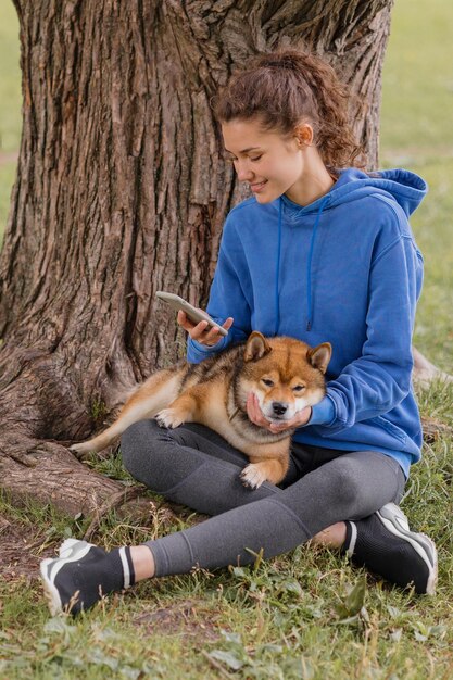Frau mit einem Hund im Park macht Sport oder Fitness auf einer Yogamatte eine europäische Frau mit Locken