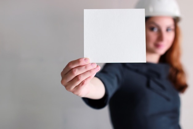 Frau mit einem leeren Blatt Papier in der Hand auf einer Baustelle