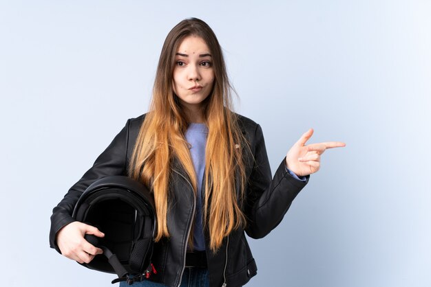 Frau mit einem Motorradhelm, der auf die Seitenteile zeigt, die Zweifel haben