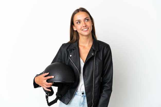 Frau mit einem Motorradhelm über lokalisiertem weißem Hintergrund, der eine Idee beim Nachschlagen denkt