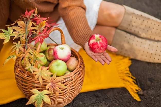 Frau mit einem reifen Apfel in einer Hand auf einem Herbstpicknick.