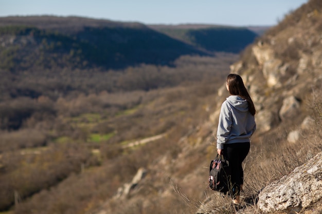 Frau mit einem Rucksack, der auf einem Felsen steht und schöne Landschaft betrachtet