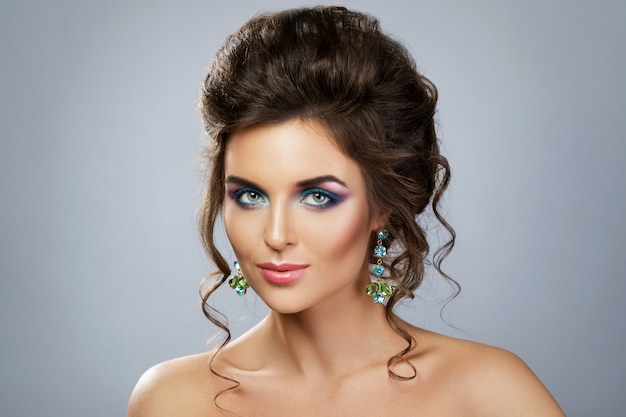 Frau mit einem schönen Make-up und Frisur, die glänzende Ohrringe trägt