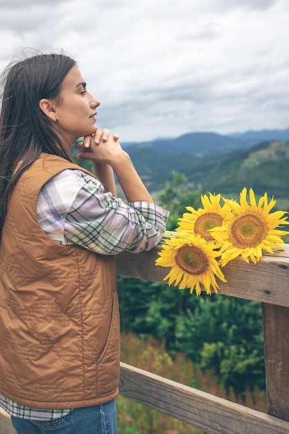 Frau mit einem Strauß Sonnenblumen in der Natur in den Bergen