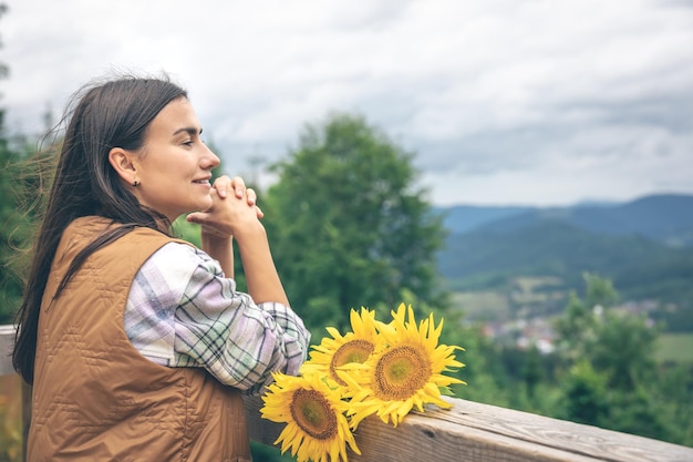 Frau mit einem Strauß Sonnenblumen in der Natur in den Bergen