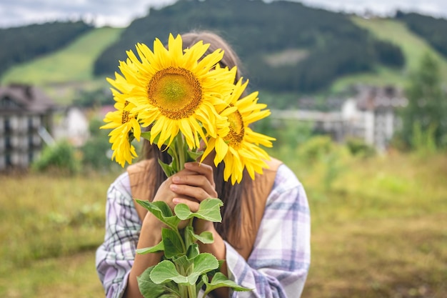 Frau mit einem Strauß Sonnenblumen in der Natur in einer bergigen Gegend