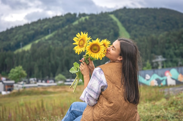 Frau mit einem Strauß Sonnenblumen in der Natur in einer bergigen Gegend