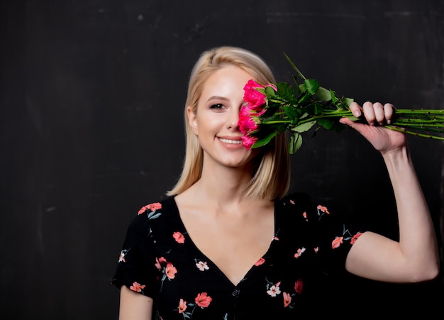 Frau mit einem Strauß von Rosen auf einem dunklen Hintergrund