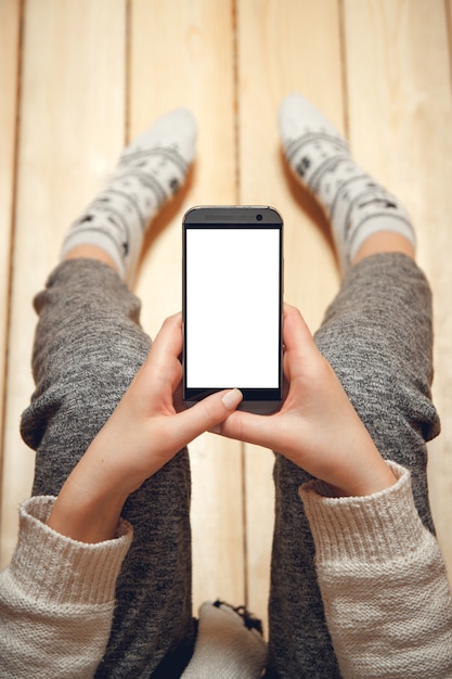 Frau mit einem Telefon in ihren Händen, die zu Hause sitzen