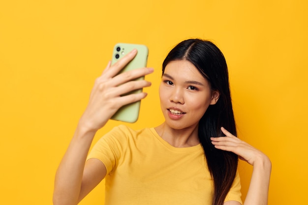 Frau mit einem Telefon in ihren Händen macht einen selfie gelben Hintergrund unverändert