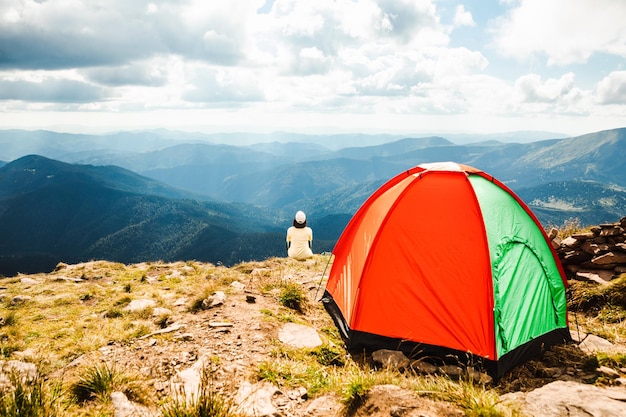 Frau mit einem Zelt auf einem Berggipfel