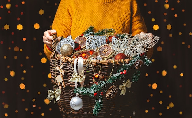 Frau mit einer Box, die einen Korb mit vielen Weihnachtsdekoration hält