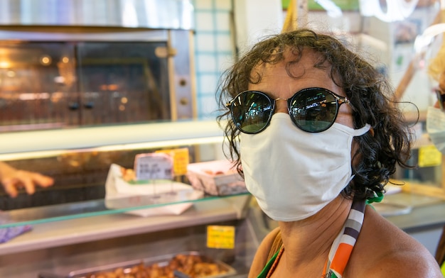 Frau mit einer Gesichtsmaske, die am Markt einkauft