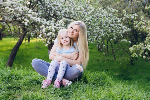 Frau mit einer kleinen Tochter, die durch den blühenden Apfel geht