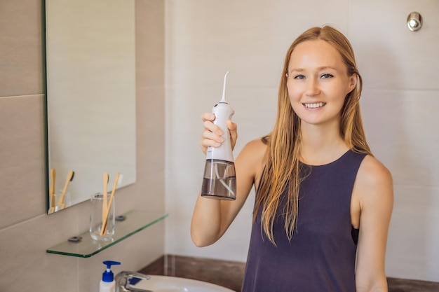 Frau mit einer Munddusche im Badezimmer