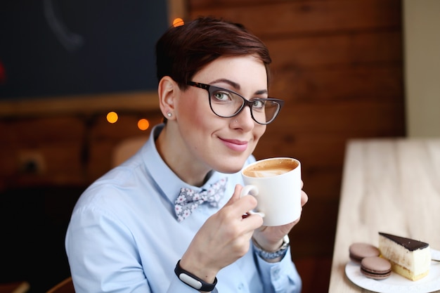 Frau mit einer Tasse Kaffee, die Kaffee trinkt und lächelt
