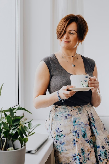 Frau mit einer Tasse Tee am Fenster