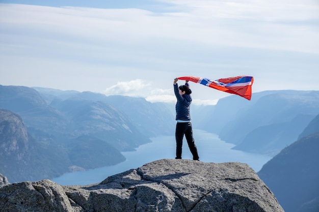 Frau mit einer wehenden Flagge Norwegens auf dem Hintergrund der Natur