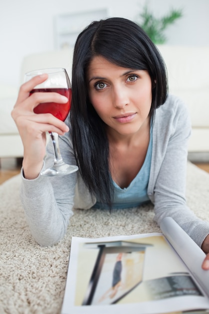 Frau mit einer Zeitschrift, die ein Glas Rotwein hält