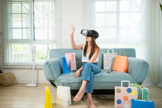 Frau mit Einkaufstaschen, die moderne Virtual-Reality-Headsets trägt und Erfahrung im Online-Shopping hat