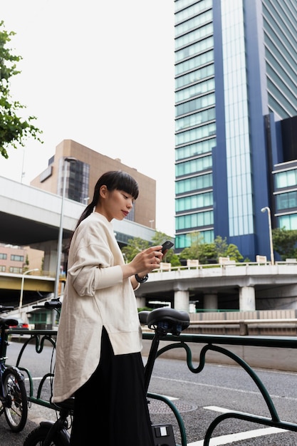 Foto frau mit elektrofahrrad in der stadt mit smartphone