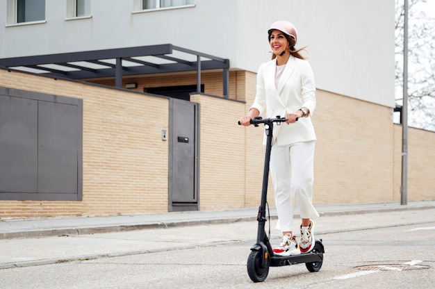 Frau mit Elektroroller und Helm in der Stadt