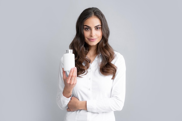 Frau mit Flasche Pillen Produkt Mädchen hält ergänzende Pillenflasche isoliert auf grauem Hintergrund