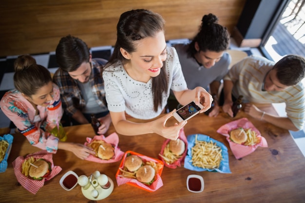 Foto frau mit freunden, die essen im restaurant fotografieren