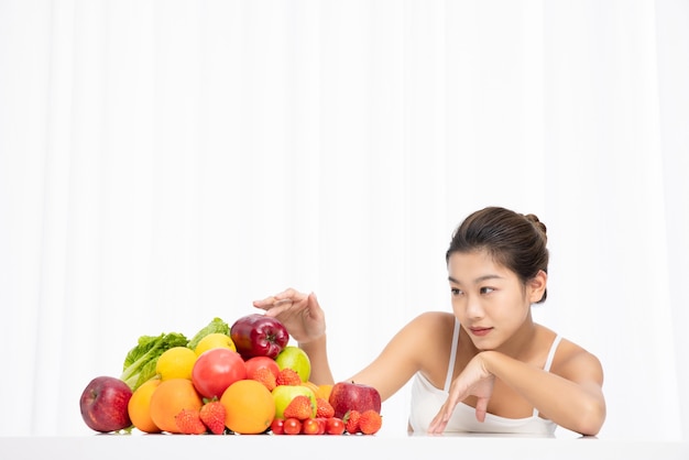 Frau mit frischen Früchten auf dem Tisch issolated auf weißem Hintergrund Diätkonzept