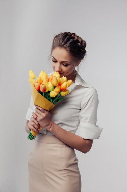 Frau mit Frühlingsblumenstrauß. Riechende Blumen der glücklichen überraschten vorbildlichen Frau.