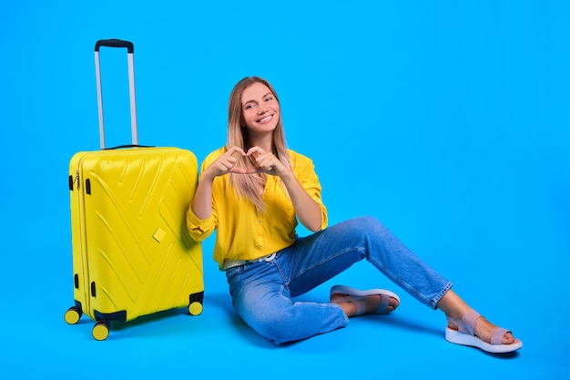 Frau mit gelbem Koffer auf blauem Hintergrund Konzept der lang erwarteten Reise Liebesreise