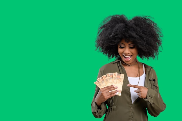 Frau mit Geld Junge lächelnde Frau mit brasilianischem Geld grüner Hintergrund