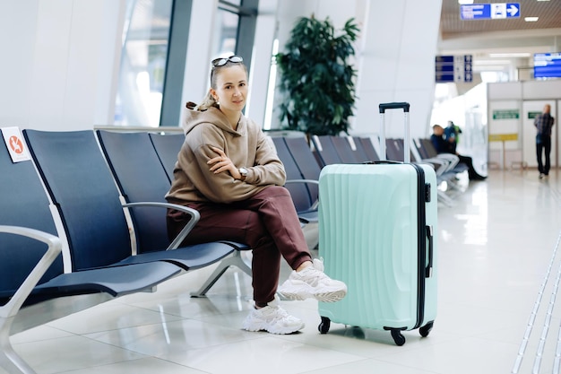 Frau mit Gepäck sitzt im Wartezimmer des Flughafens