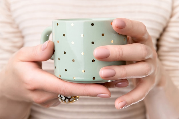 Frau mit gepflegten Händen mit nacktem beigem rosa Nageldesign, der Tasse hält. Maniküre-, Mode- und Schönheitssalonkonzept