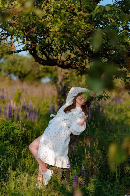 Foto frau mit geschlossenen augen in einem eleganten kleid, die auf einem baum liegt