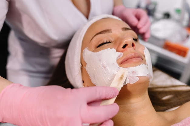 Frau mit Gesichtsmaske aus Ton im Beauty Spa