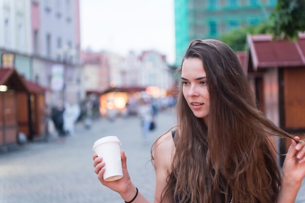 Frau mit Getränk zum Mitnehmen Spaziergang auf der Straße Sexy Frau hält Einweg-Kaffeetasse Schönheitsmädchen