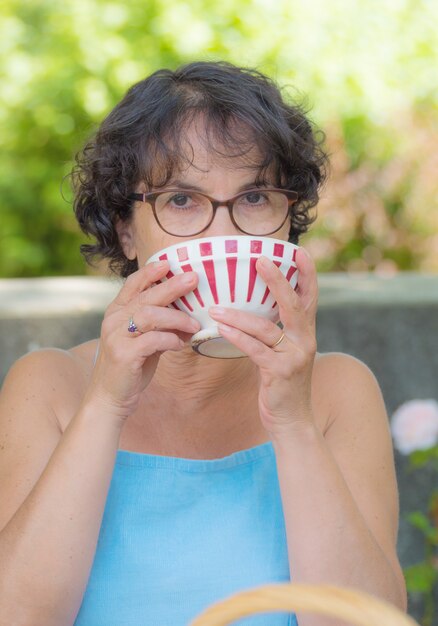 Frau mit Gläsern, die eine Tasse Tee trinken