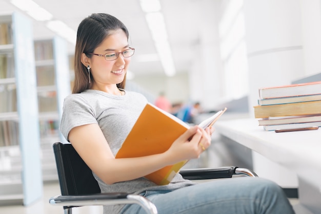 Frau mit gläsern ein buch in der bibliothek lesend.