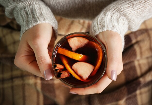 Frau mit Glasbecher köstlichen Weihnachtsglühwein in den Händen, Nahaufnahme