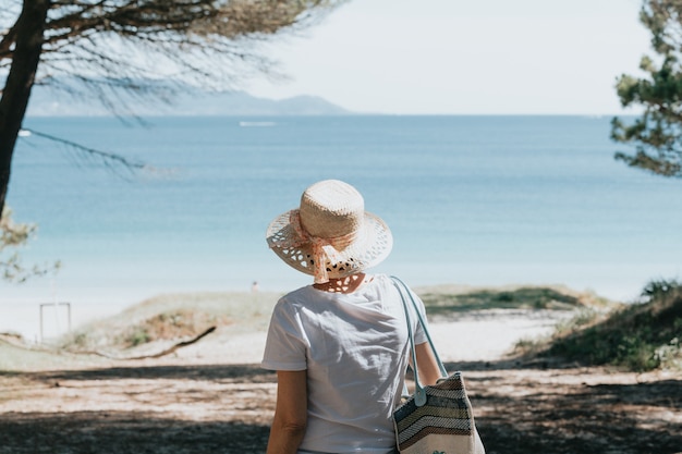 Frau mit grauen Haaren am Strand während eines super sonnigen Tages Seniorenfreiheitskonzept Kopie Raum Sonne