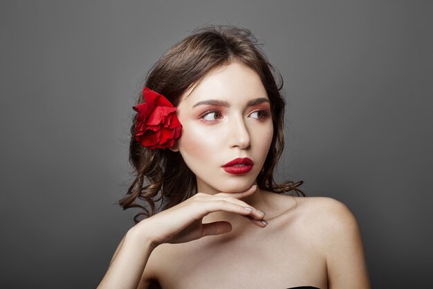 Frau mit großer roter Blume in ihrem Haar. Braune Haare