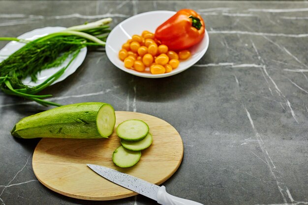 Foto frau mit händen hält frischen salat, während sie am küchentisch steht, voller frischer gemüsesalatschüssel