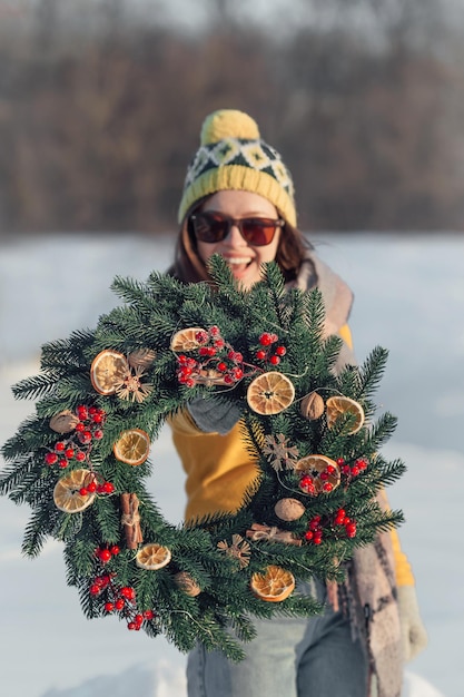 Frau mit handgemachten Weihnachtskränzen auf Winterhintergrund