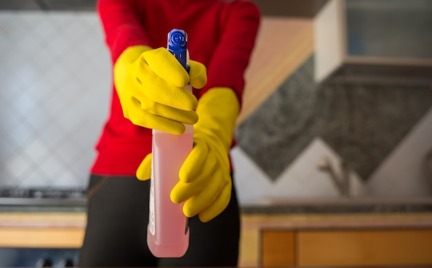 Foto frau mit handschuhen hält ein desinfektionsspray in der hand