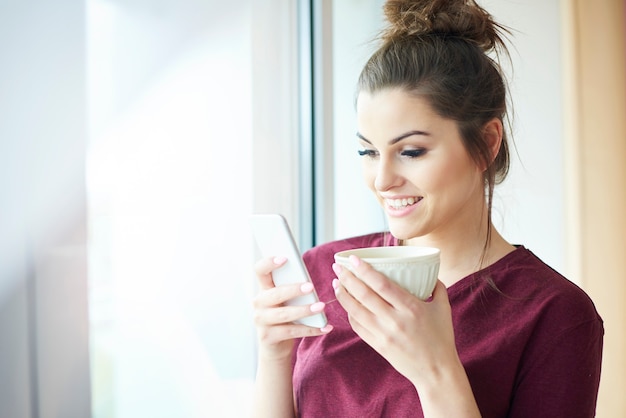 Frau mit Handy beim Kaffeetrinken