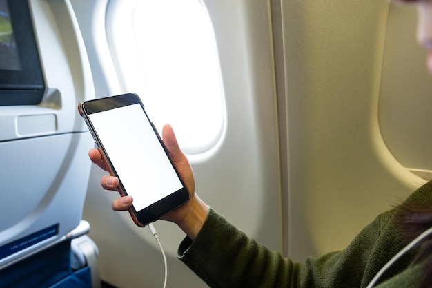 Frau mit Handy im Flugzeug