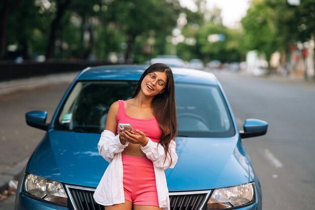 Frau mit Handy in der Nähe des Autos auf der Straße