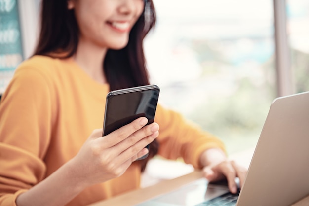 Frau mit Handy und Laptop zu Hause