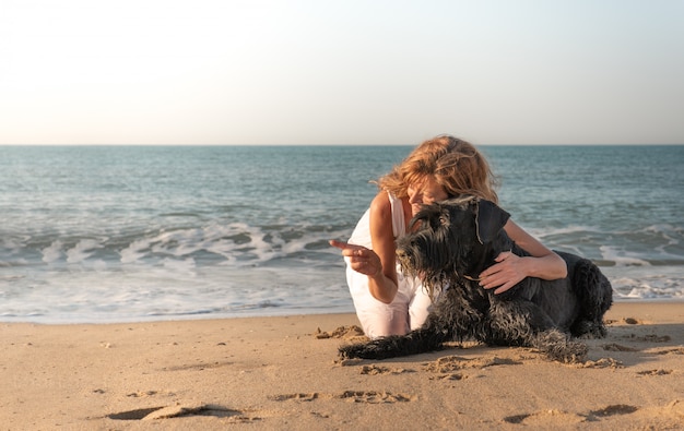 Frau mit Hund an der Küste zeigt